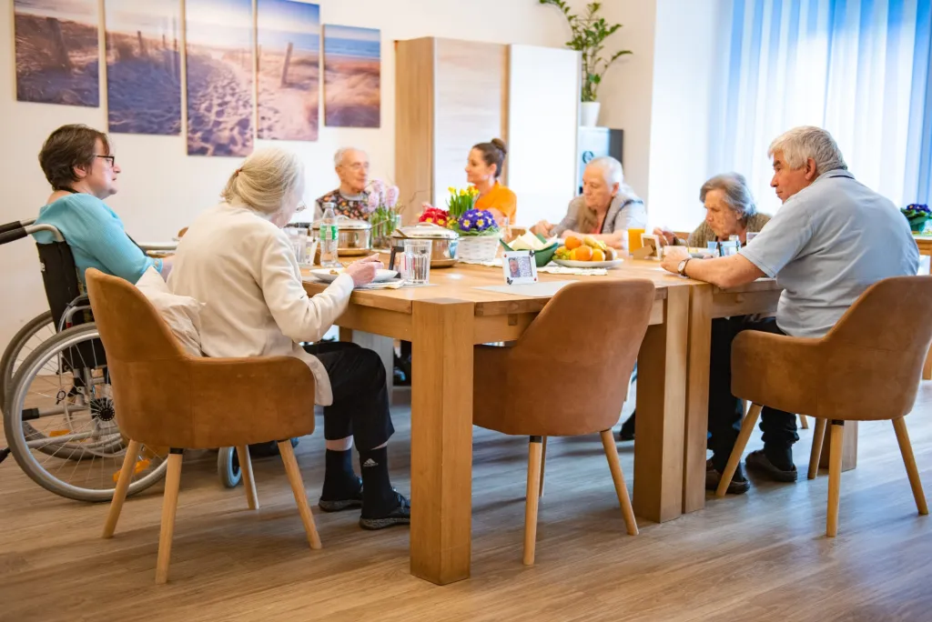 ARCHIMED Pflegekraft betreut Senioren im gemeinsamen Essbereich